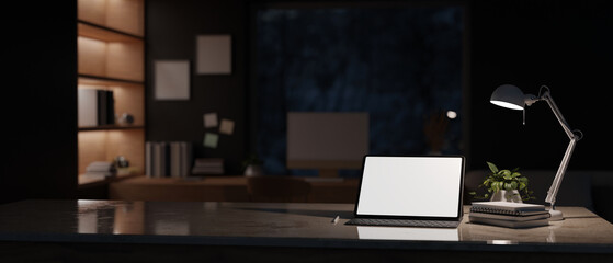 Canvas Print - modern office at night with tablet mockup on table over blurred dark office room in background.