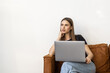 © F8  \ Suport Ukraine - Young woman wearing casual clothes, lounging on a grey sofa isolated on a white background.