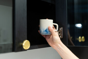 Wall Mural - woman take cup from dark wood cupboard, closeup