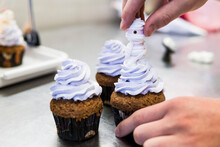 Chef Hand Is Adding A Soft Mummy On  A Blueberry Butter Cream Cupcake
