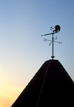 A Weather Vane Perched Atop A Mountain-town Building.