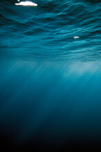 An Underwater View Of The Ocean Surface With Sun Rays.