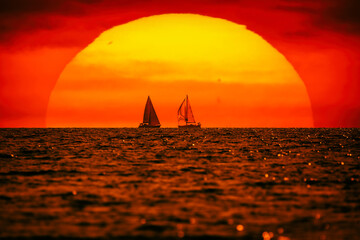 Wall Mural - Silhouette of a sailing boat in sunset sunrise time and ocean horizon.