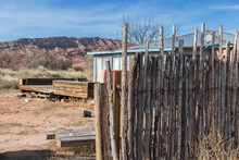 Abandoned House Behind A Wooden Pole Fence With Desert Mountains In The Background