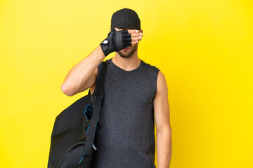 Wall Mural - Young sport blonde man with sport bag isolated on yellow background covering eyes by hands. Do not want to see something