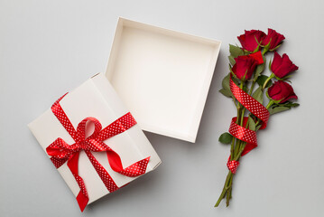 Wall Mural - Valentines day gift box with red roses on color background, top view