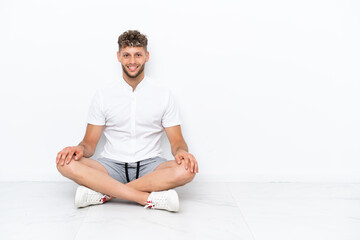 Wall Mural - Young blonde man sitting on the floor isolated on white background laughing