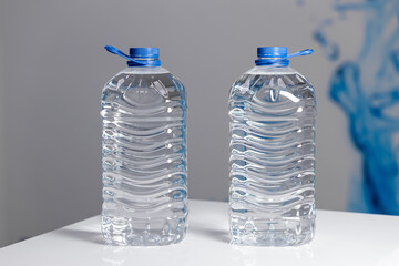 Two full 5 liter bottles of water on a white table on a gray background. Water delivery