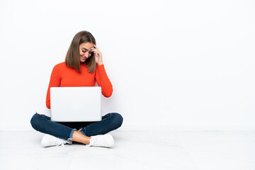 Wall Mural - Young caucasian woman sitting on the floor with a laptop laughing