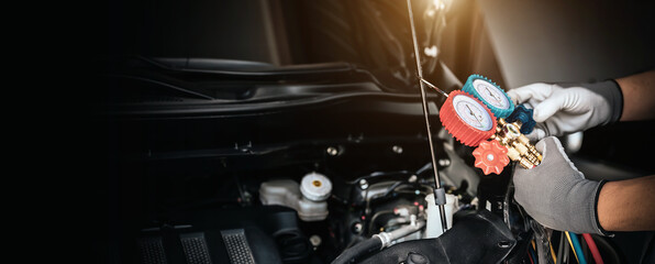 Hand of car mechanic technician use meter to check car air conditioner system heat problem and fix repairing and filling air refrigerant.