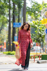 vietnamese girl with ao dai dress walking on street, ho chi minh city, vietnam. ao dai is famous tra