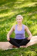 © GRON777 - Happy athletic middle aged woman doing yoga outdoors barefoot in lotus position.Does sports in the city park. The concept of meditation.