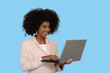 © Edson Souza - young woman typing on laptop computer keyboard looks at screen and smiles, black woman on blue background