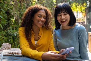 Two smiling friends using mobile phone 