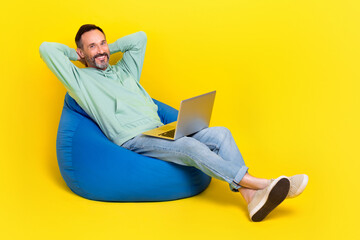 Poster - Full length photo of pretty dreamy man wear green sweatshirt hands arms behind head modern gadget beanbag isolated yellow color background