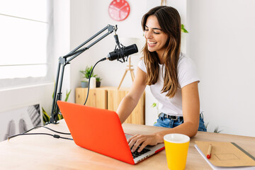 Smiling young pretty host woman recording radio podcast at home studio. Technology trend concept