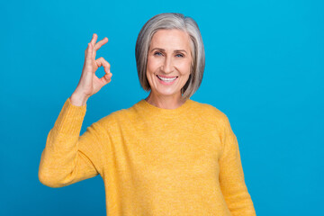 Sticker - Photo portrait of mature lovely lady showing okey symbol positive feedback dressed stylish yellow clothes isolated on blue color background