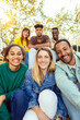 © Xavier Lorenzo - Vertical shot of young student people smiling at camera sitting outdoors. Group photo of millennial friends laughing together resting in city street.