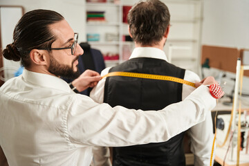 Wall Mural - Focused couturier taking customer body measurements using tape measure