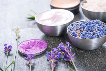 Poster - beauty product samples with fresh purple and blue dried lavenders, bath salts and massage pouches on dark wood table background