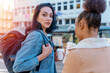 © Iryna - two women in a denim jacket is talking to each other , drinking coffee  and waiting for a tram at the stop Lifestyle photo