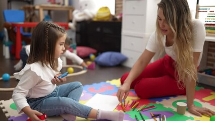 Poster - Teacher with boy and girl sitting on floor drawing on paper and playing with car at kindergarten