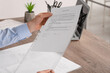 © New Africa - Businessman putting document into punched pocket at wooden table in office, closeup