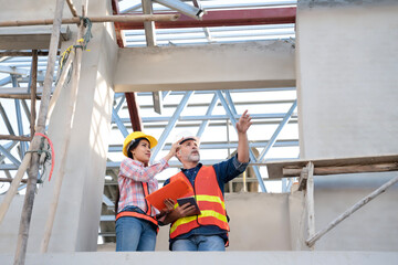 Civil engineer manager working at real estate site with assistant, inspect houses construction project progress, utilities by comparing with online blueprint in tablet. House builder worker. 