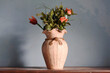 Ancient ceramic flower vase placed on table with dried flowers