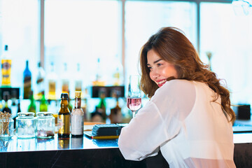 Wall Mural - A Pretty woman smile and sit on rooftop bar for party time with pink cocktail glass in her hand