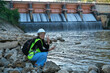 © Pornpimon - Environmental engineer uses a mobile phone to record water analysis data in dam. Environmentalists collect water samples from the dam to check for contamination. Water and ecology concept
