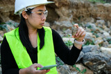 Fototapeta Uliczki - Female geologist using mobile phone to record data analyzing rocks or gravel. Researchers collect samples of biological materials. Environmental and ecology research.