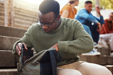 university, student and black man looking in bag at campus for learning, studying or lost knowledge 