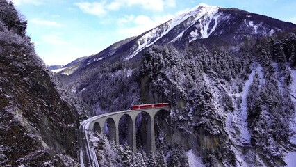 Wall Mural - Aerial view of Train passing through famous mountain in Filisur, Switzerland. Landwasser Viaduct world heritage with train express in Swiss Alps snow winter scenery. 