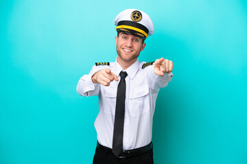 Poster - Airplane caucasian pilot isolated on blue background points finger at you while smiling