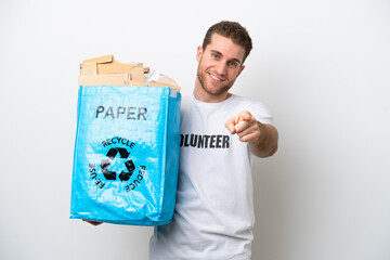 Wall Mural - Young caucasian man holding a recycling bag full of paper to recycle isolated on white background pointing front with happy expression