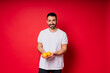 © Ivan Zelenin - Portrait of young bearded man holding lemons in both hands on isolated red background