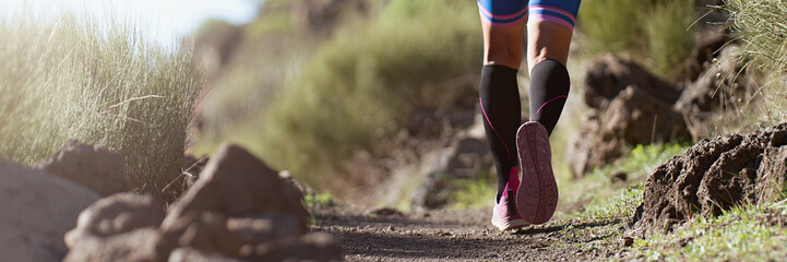 Wall Mural - Trail running athlete exercising for fitness and health outdoors on mountain pathway, closeup of running shoes in action