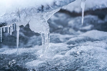 Ice On Frozen River, Closeup Detail, Water Flows Over Rocks Forming Waves And Bubbles - Winter Background