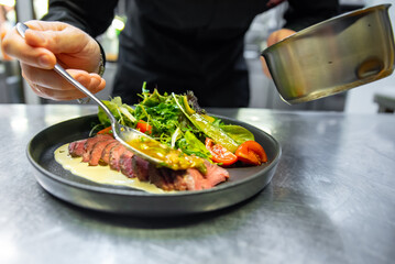 Sticker - chef hand preparing Roastbeef salad with vegetables on restaurant kitchen