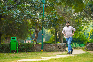 Wall Mural - Young indian man running or jogging at park.