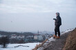 osoba w kapturze stojąca na wzgórzu z aparatem