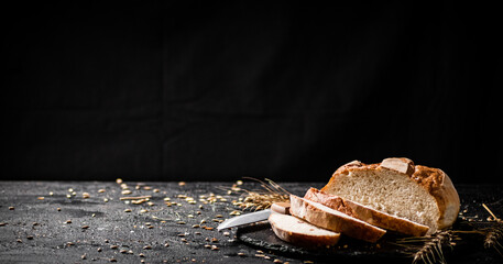 Poster - Sliced on a stone board wheat bread with grains. 