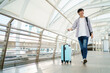 © DG PhotoStock - Happy cheerful Asian handsome young man walking in the city railway station alone with suitcase.