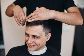 Wall Mural - hairdresser does haircut for man in barber shop