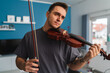 A portrait of a young guy playing or learning a violin in his home private classes online course for violin music