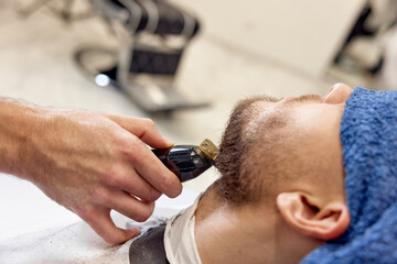 Wall Mural - Barber shaving bearded man in barber shop.