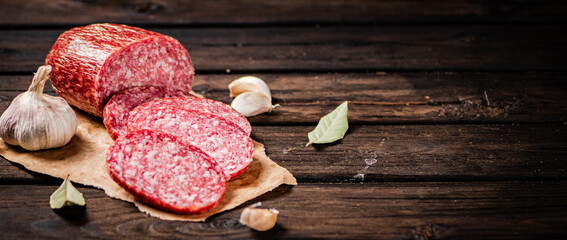 Sticker - Pieces of salami sausage with garlic and bay leaf on paper. 