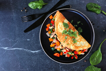 Wall Mural - Healthy vegetable loaded omelette. Overhead view corner border over a dark stone background.