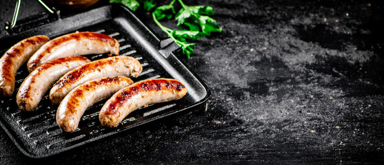 Canvas Print - Grilled sausages in a frying pan with parsley. 